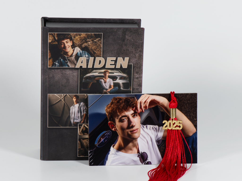 Photo cover image box of a senior guy with a photo print and graduation tassel sitting in front of the box. 